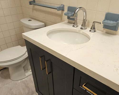 Modern bathroom vanity with dark navy cabinets, white quartz countertop, and chrome fixtures