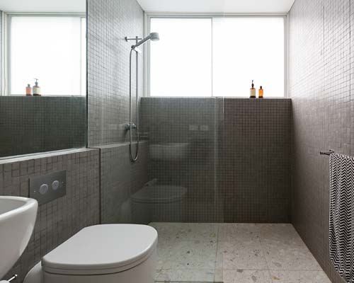 Modern walk-in shower with gray mosaic tile walls and glass partition