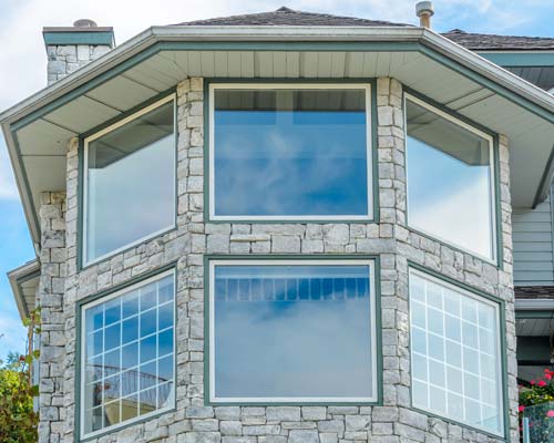 Corner of stone-accented home with large picture windows and casement windows